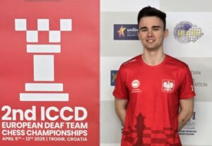 Mężczyzna w czerwonej koszuli stoi obok szachownicy